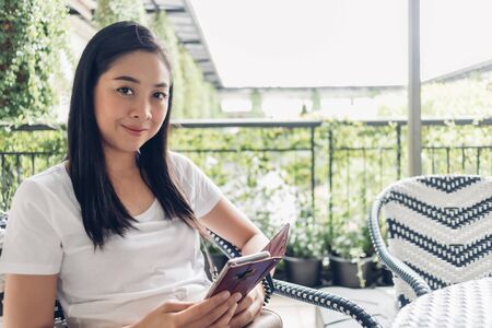 Asian woman is using her smartphone while sitting in the public cafe.の写真素材