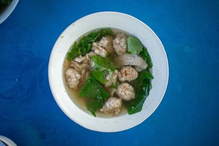 Top view of Thai style pork soup served in a bowl on blue table.の写真素材