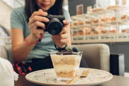 Asian woman is taking a photo of her blueberry cheesecake.