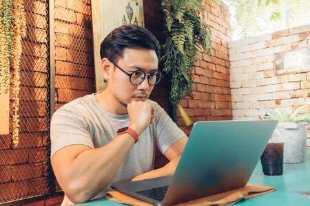 Asian man is working on his laptop in the cafe.の写真素材