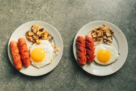 Breakfast set of sausages fried eggs and mushroom on the kitchen counter by the window in warm...