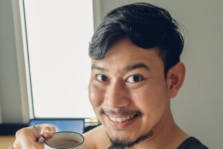 Happy smile Asian man selfie himself with hot cup of coffee in a warm cozy day.の写真素材