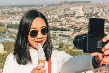 Asian woman tourist is taking selfie of herself with landscape view of Tbilisi city from the moutain...