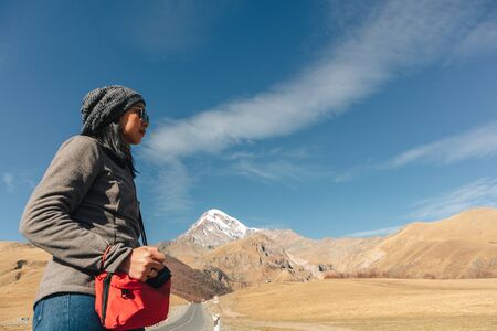 Asian tourist woman walking on the road through the mountains in concept of seeking adventure.