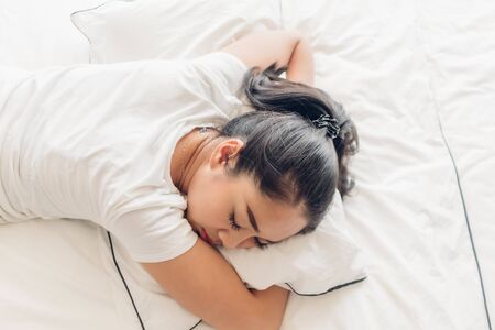 Asian woman is sleeping on her white bed in the apartment.の写真素材