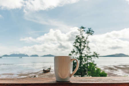 Morning coffee mug with low tide sea view as background.の写真素材