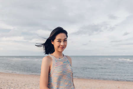 Asian woman takes a walk on the windy beach and sunny sun.の写真素材