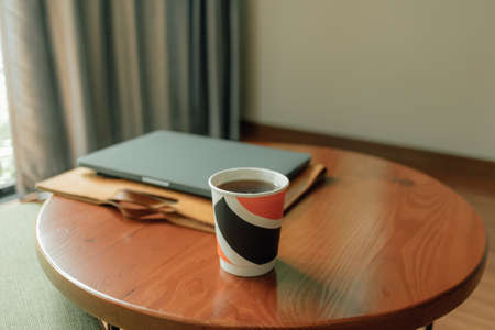 Paper cup of hot drink and laptop on the table. Concept of work from home.の写真素材