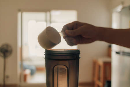 Man put Whey protein powder into the shake bottle.