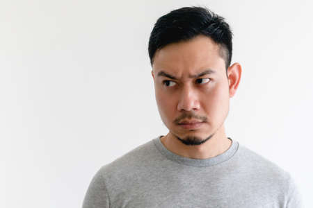 Asian man in a grey t-shirt is looking at the empty space on isolated white background.の写真素材