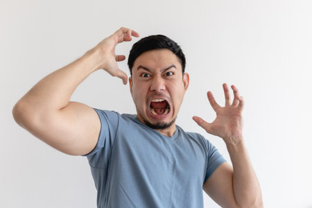 Angry and mad face of Asian man in blue t-shirt on isolated background.の写真素材