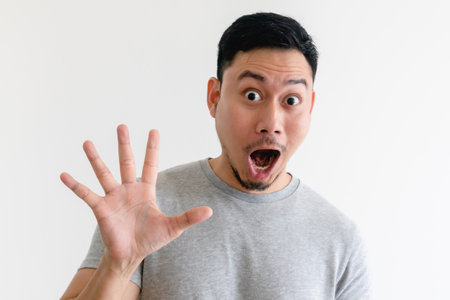 Surprised face Asian man making number hand sign on isolated white background.の写真素材