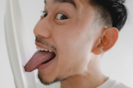 Funny face Asian man is licking white dish in concept of very delicious meal.の写真素材