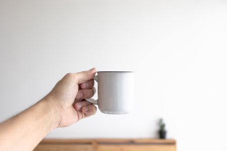White small mug of coffee in a white cozy room in the morning.