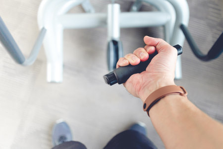 Close up of mans hand pull cable weight in a fitness gym.