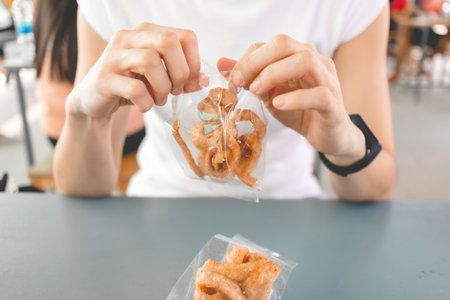 Woman in white t-shirt eats pork rind or pork crackling with Thai noodle.の写真素材