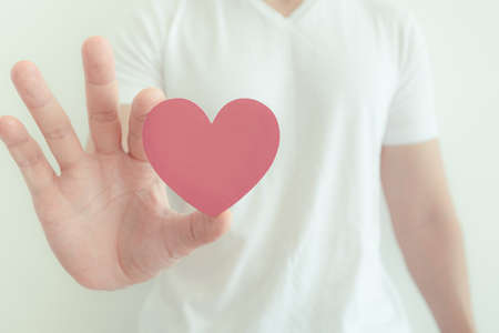 Man in white t-shirt shows pink heart shape in concept of love and Valentine.の写真素材
