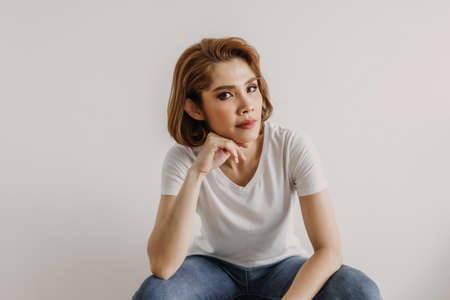 Cool looks of an Asian woman in a t-shirt and jeans relax in her apartment room.の写真素材