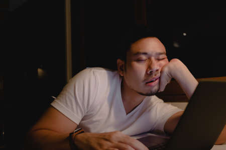 Asian man sleep on the laptop while working late at night. Concept of tired.の写真素材