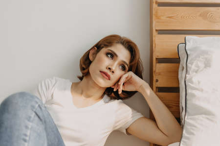 Cool looks of an Asian woman in a t-shirt and jeans relax in her apartment room.
