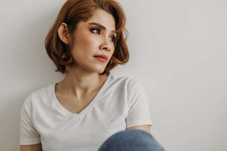 Cool looks of an Asian woman in a t-shirt and jeans relax in her apartment room.の写真素材