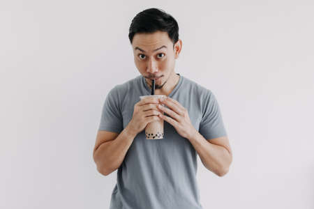 Asian man drinking boba tea or bubble tea deliciously isolated on white background.の写真素材