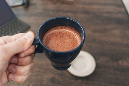 Close up of hand holding a cup of hot cocoa in a cafe.の写真素材