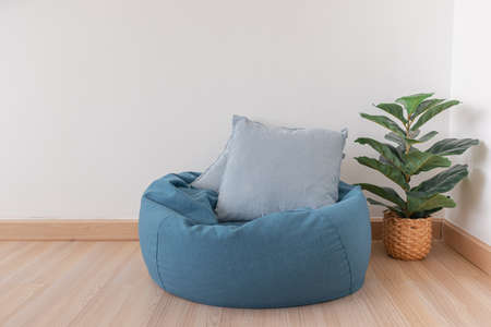 Blue bean bag in a clear living room with wooden floor and clear white wall.の写真素材
