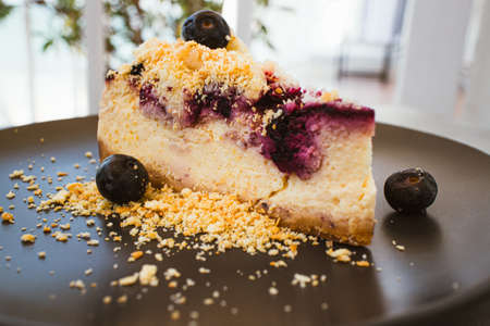 Blueberry cheese cake on black plate in the cafe.の写真素材