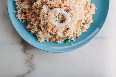 Thai style Squid Fried Rice served in blue ceramic dish on white table.の写真素材
