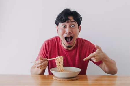 Wow and surprised funny face of Asian man eat instant noodle.の写真素材