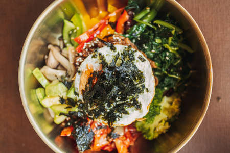 Close up of Bibimbap or Korean rice dish served on wooden table.の写真素材