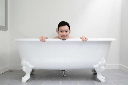 Asian man is having a good time in a white bathtub.の写真素材