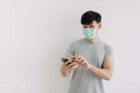 Asian man wear mask and using phone application isolated on white background.の写真素材