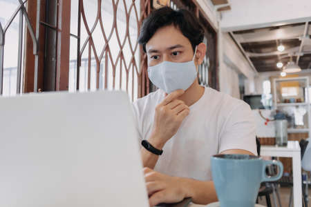 Asian man work in cafe with mask on the face. Concept of freelance