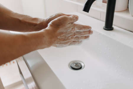 Washing hands with white foam in the toilet. Concept of cleaning and protection.