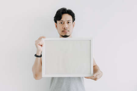 Serious face Asian man holding an empty frame isolated on white background.の写真素材