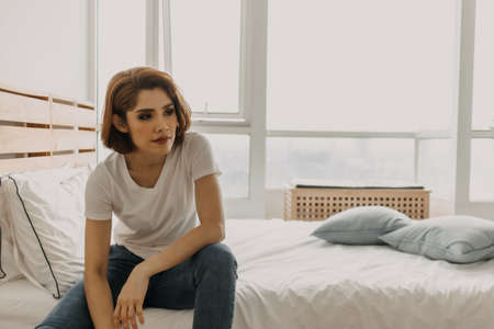 Cool looks of an Asian woman in a t-shirt and jeans relax in her apartment room.の写真素材