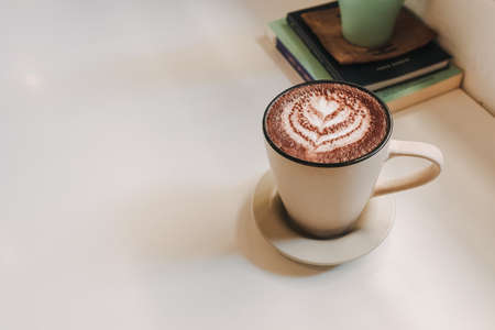 Hot latte coffee served in white mug on the table in warm morning.の写真素材