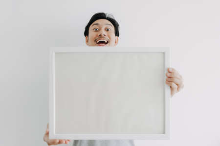 Happy Asian man holding an empty photo frame isolated on white background.の写真素材