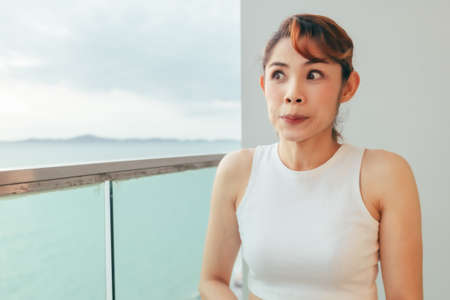 Close up of Asian woman relax on the hotel balcony with sea view in summer.