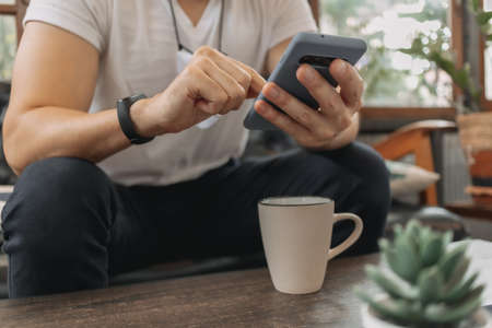 Asian man with mask is using smartphone and drink coffee in the cafe.
