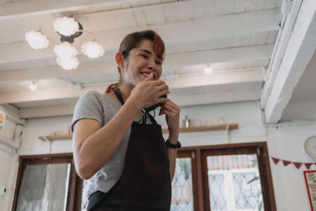 Portrait of happy Asian woman cafe and restaurant owner with face mask.の写真素材