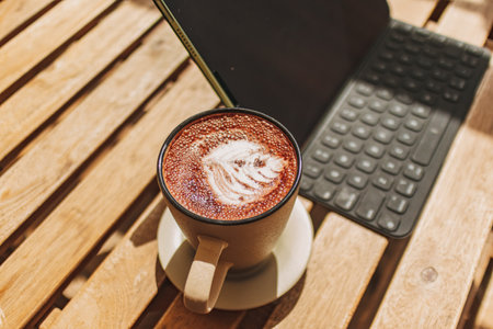 Laptop or tablet with hot coffee on the desk with warm sun of summer.