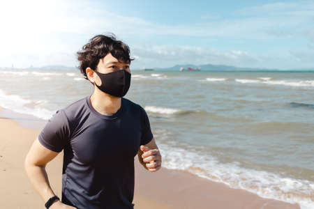 Asian man jogging on the beach with mask in summer morning.の写真素材