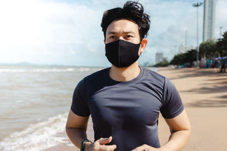 Asian man jogging on the beach with mask in summer morning.の写真素材
