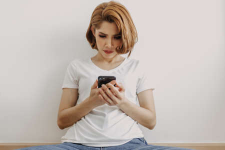 Asian woman resting and relax in the room with her smartphone in hand.