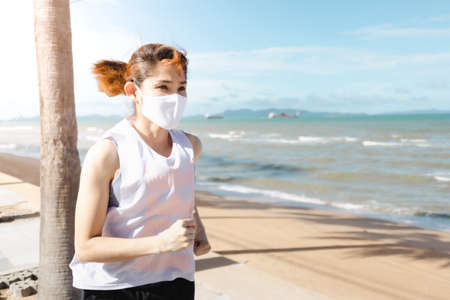 Asian woman jogging by the beach in the morning of warm summer.