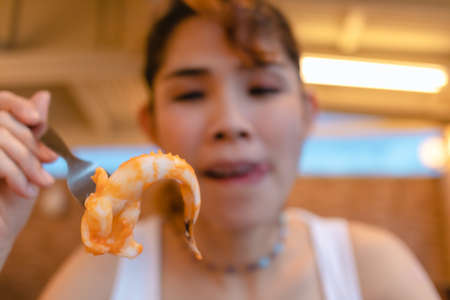 Happy Asian woman enjoy eating squid seafood in the summer vacation.