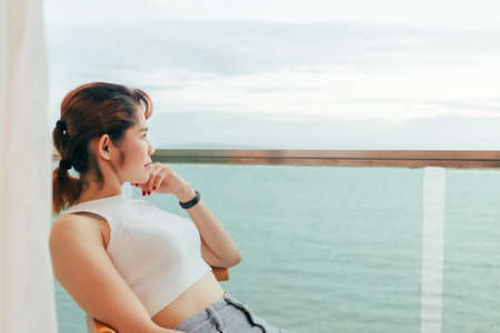 Close up of Asian woman relax on the hotel balcony with sea view in summer.の写真素材